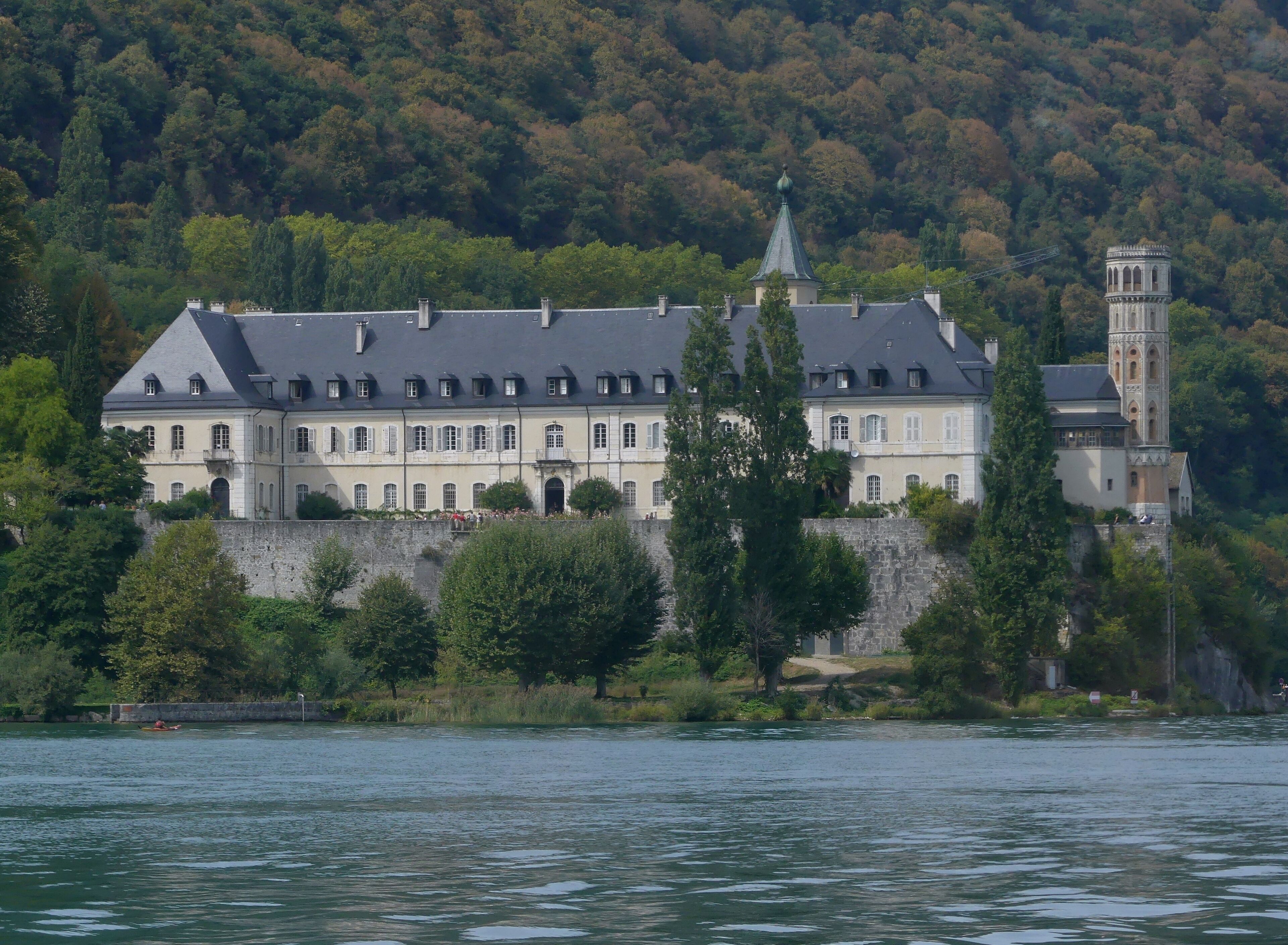 A large, historic building with a tower and a river in the foreground.