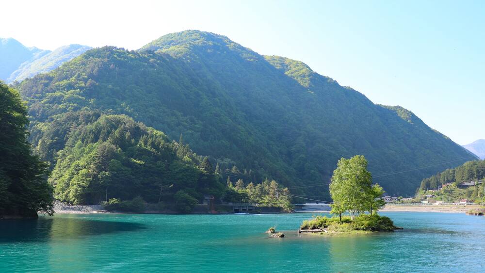 A mountain with a lake in the foreground and a small island with trees.