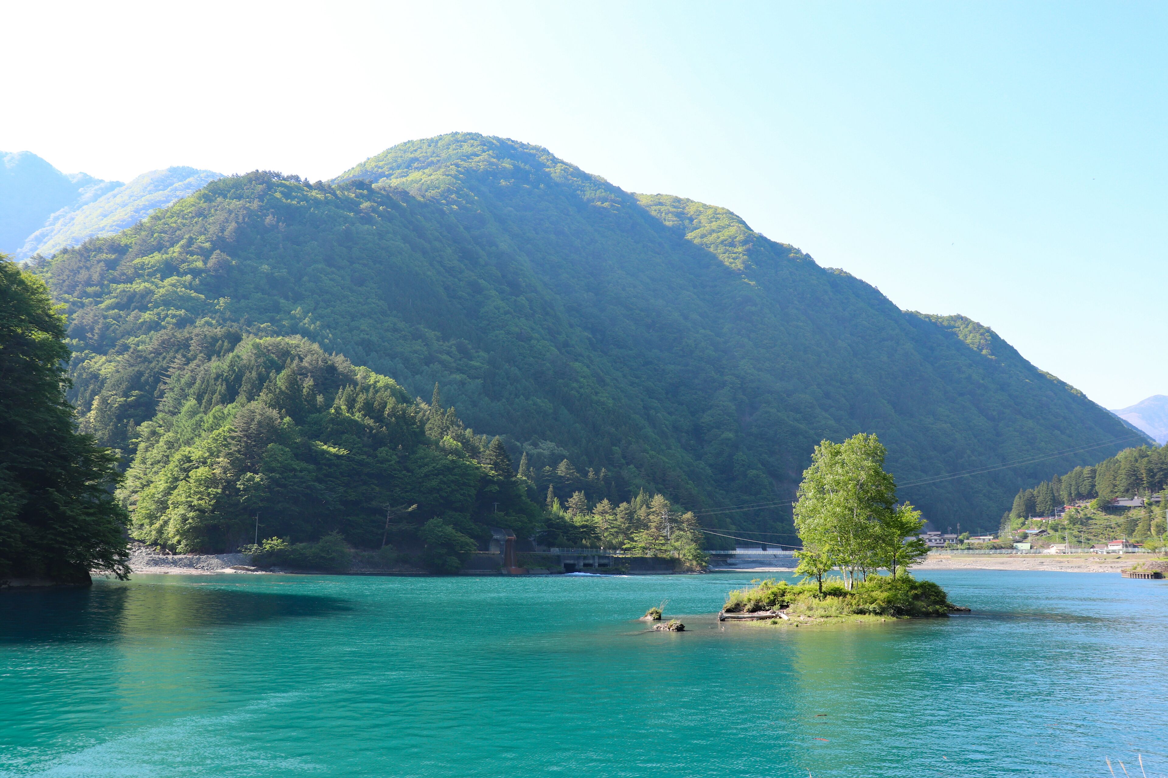 A mountain with a lake in the foreground and a small island with trees.