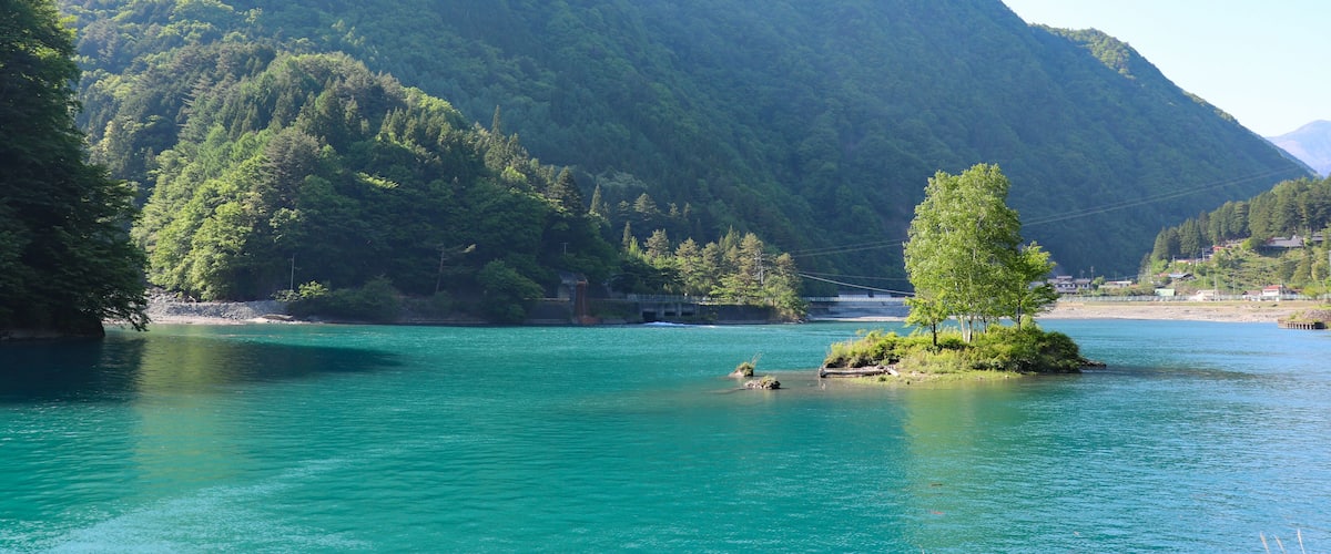A mountain with a lake in the foreground and a small island with trees.