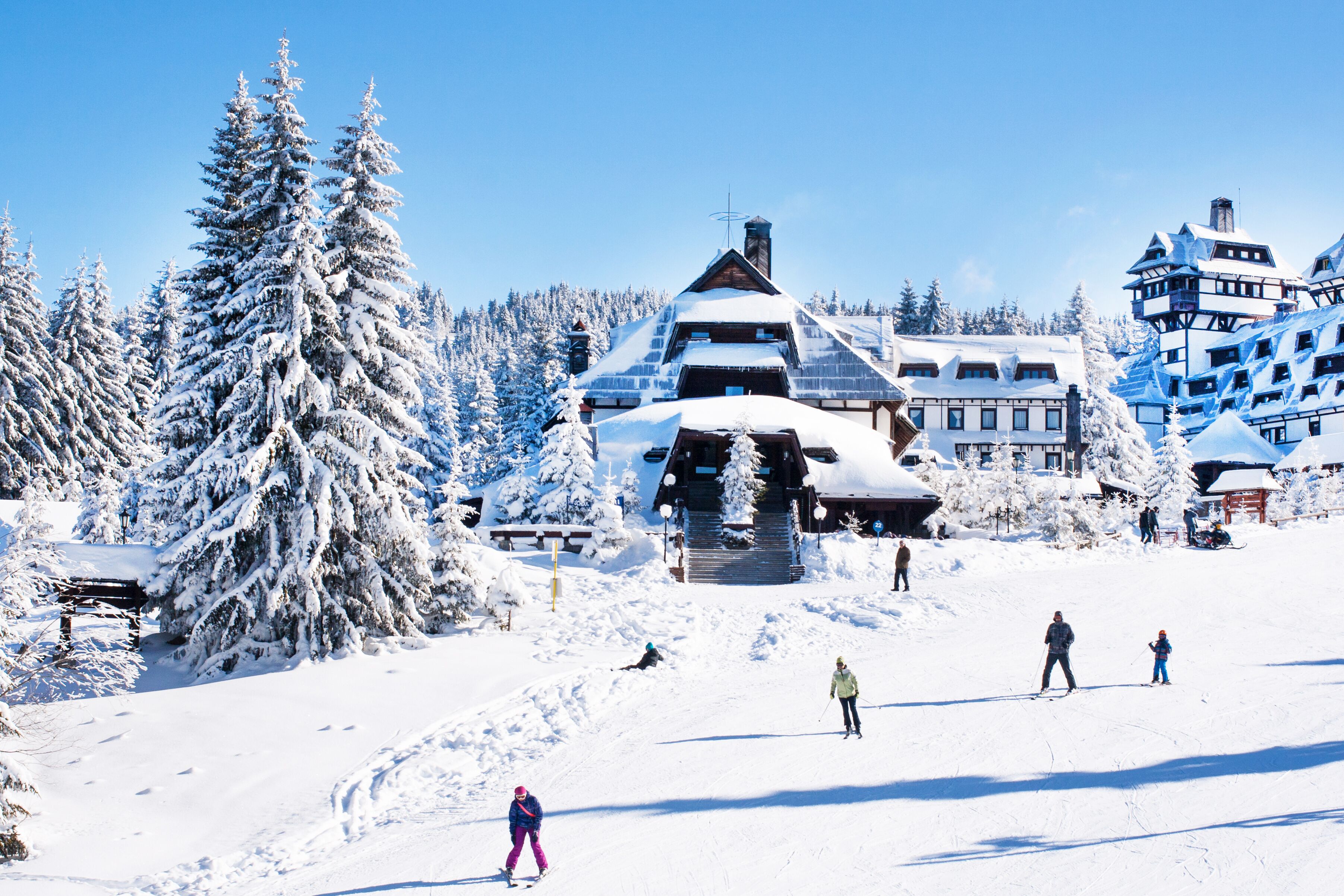 Panorama of ski resort Kopaonik, Serbia, ski slope, chalet houses covered with snow, people skiing