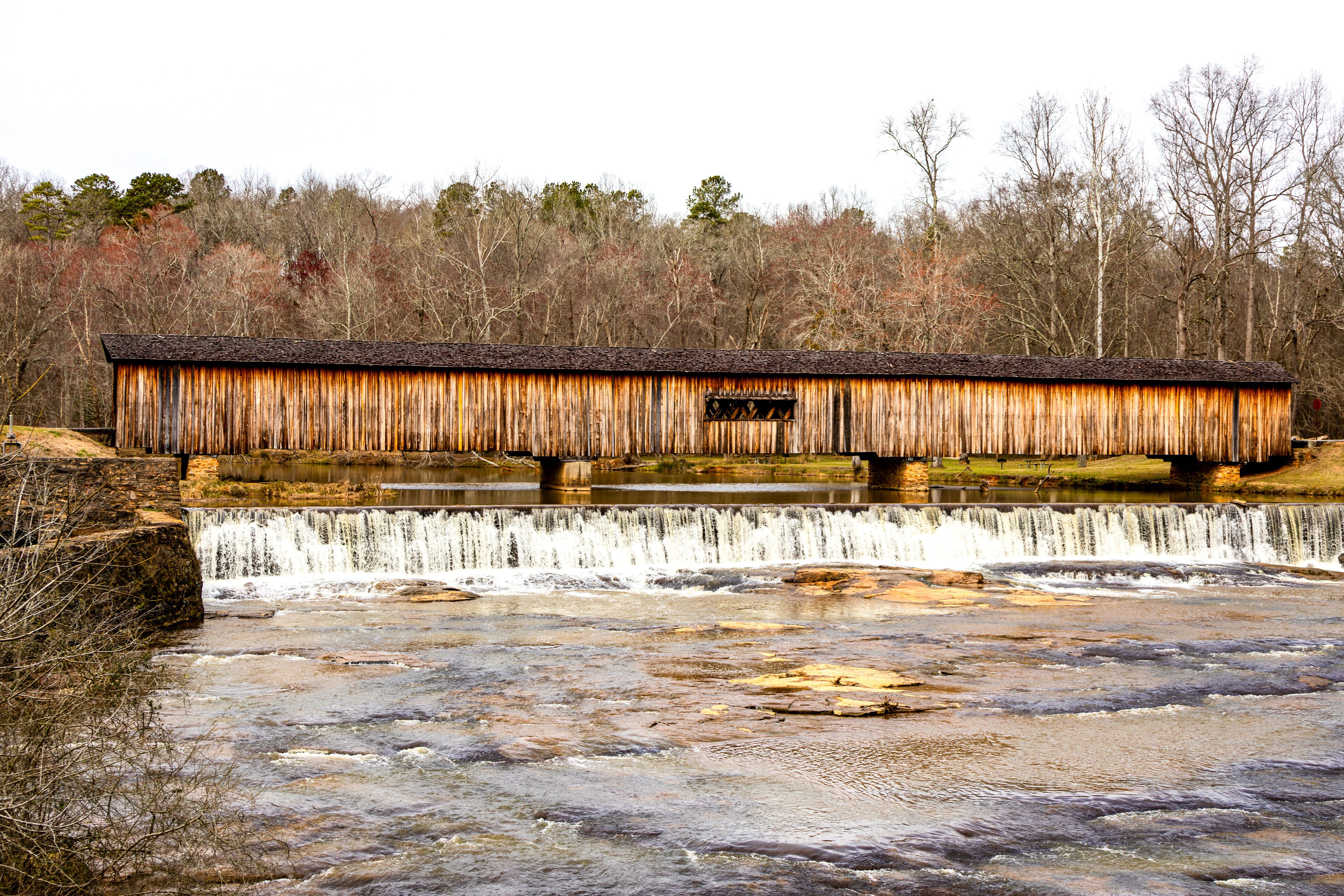 A rustic wooden bridge over a waterfall.