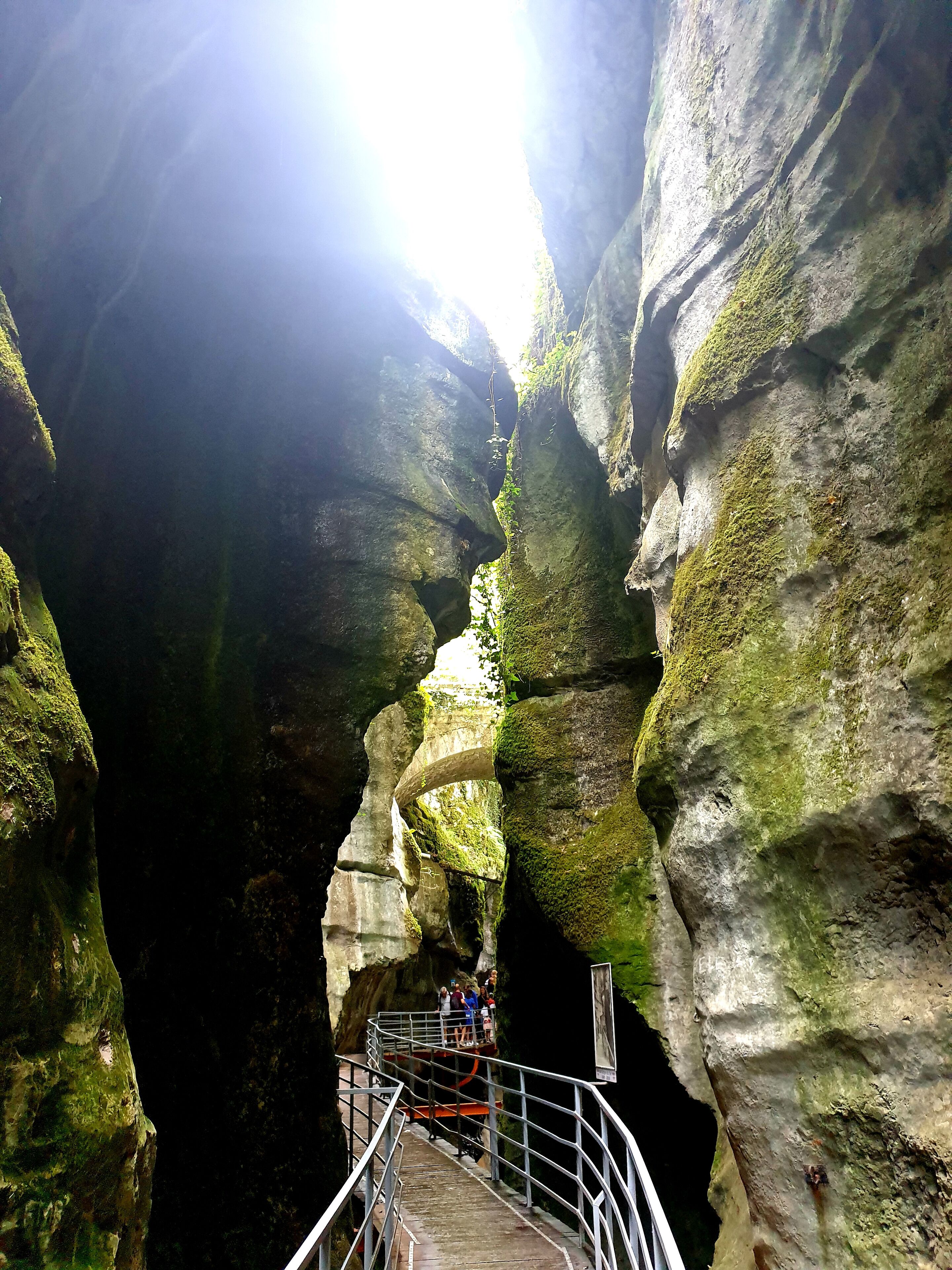 A narrow rock passage with a metal walkway and a viewing platform.