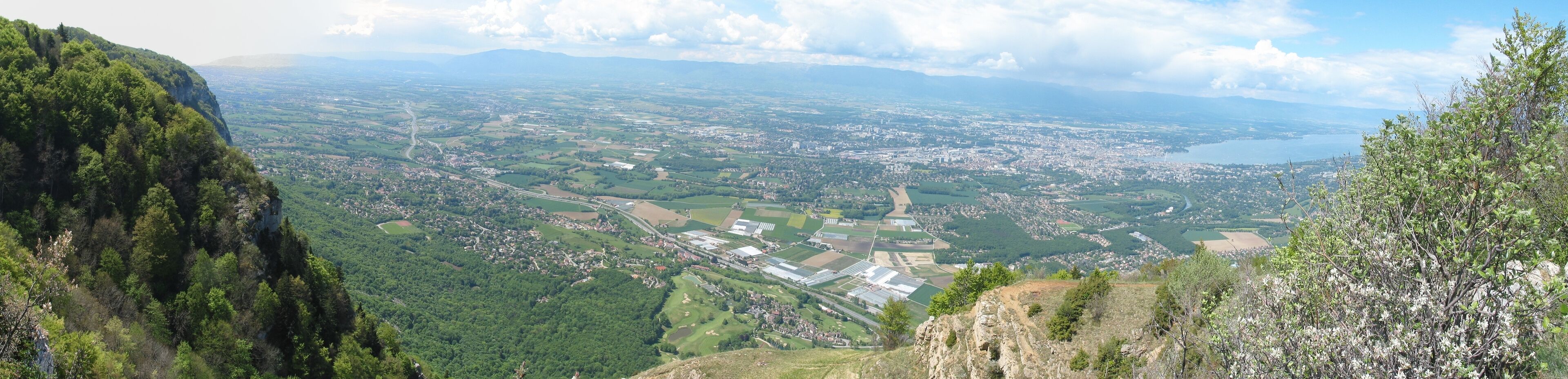A panoramic view of a valley with a river, fields, and a town.