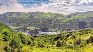 A valley with a lake surrounded by green hills and mountains.