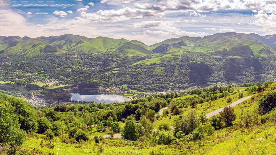 A valley with a lake surrounded by green hills and mountains.