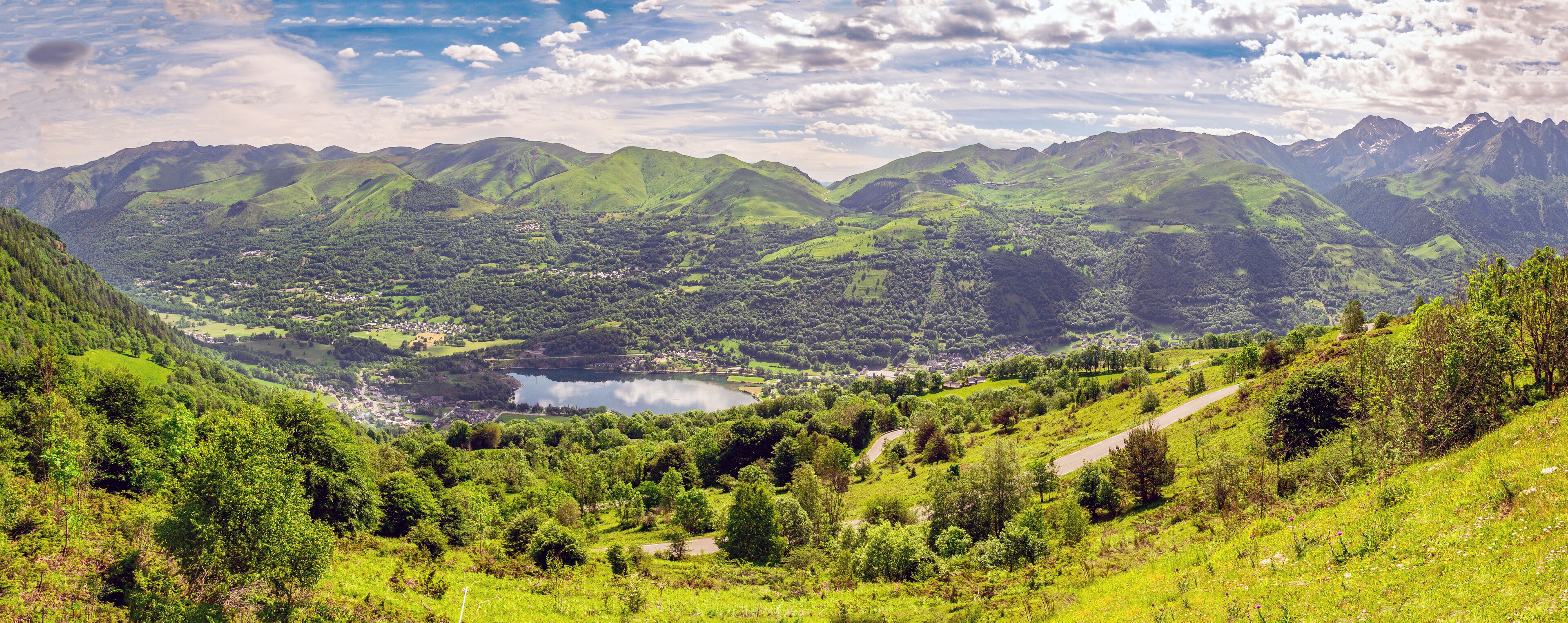 A valley with a lake surrounded by green hills and mountains.