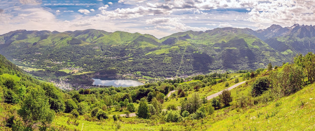 A valley with a lake surrounded by green hills and mountains.