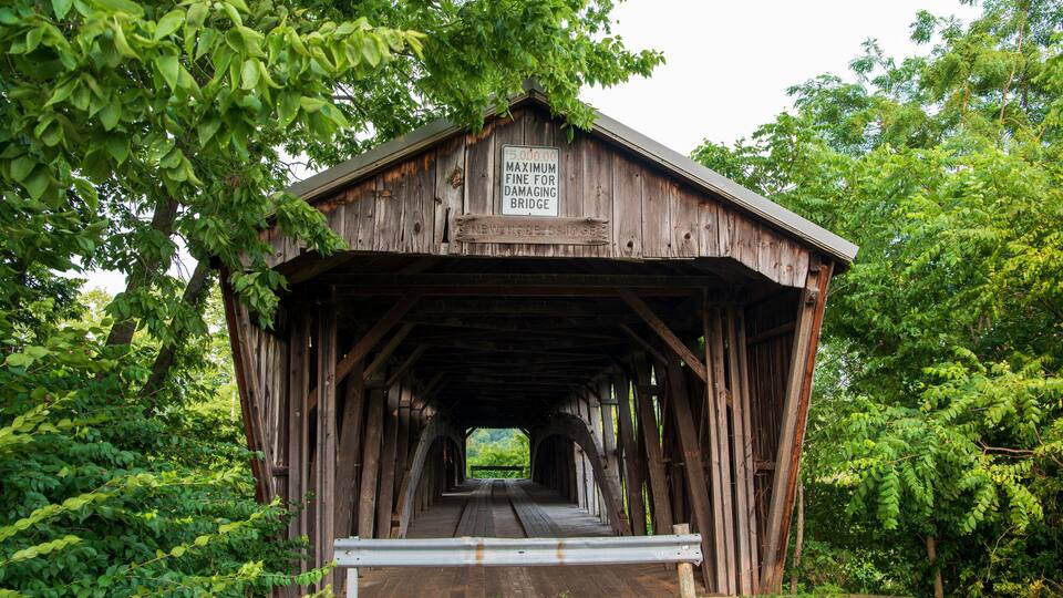 A wooden covered bridge with a sign indicating a maximum fine for damaging it.