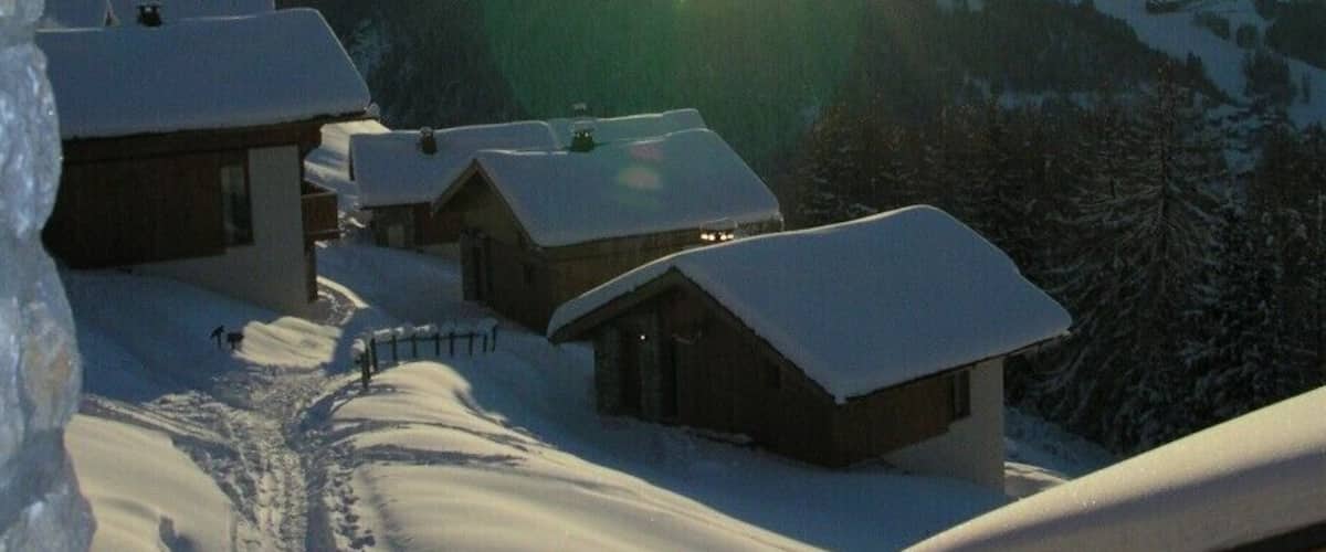 A snowy mountain village with wooden cabins and a clear sky.