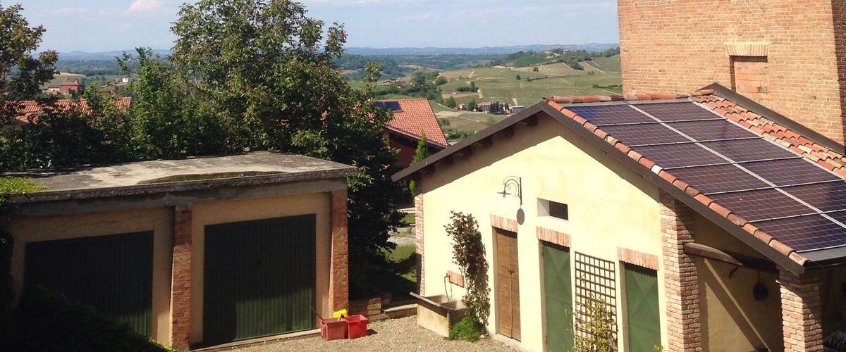 A rural landscape with a brick house, a garage, and a solar panel installation.