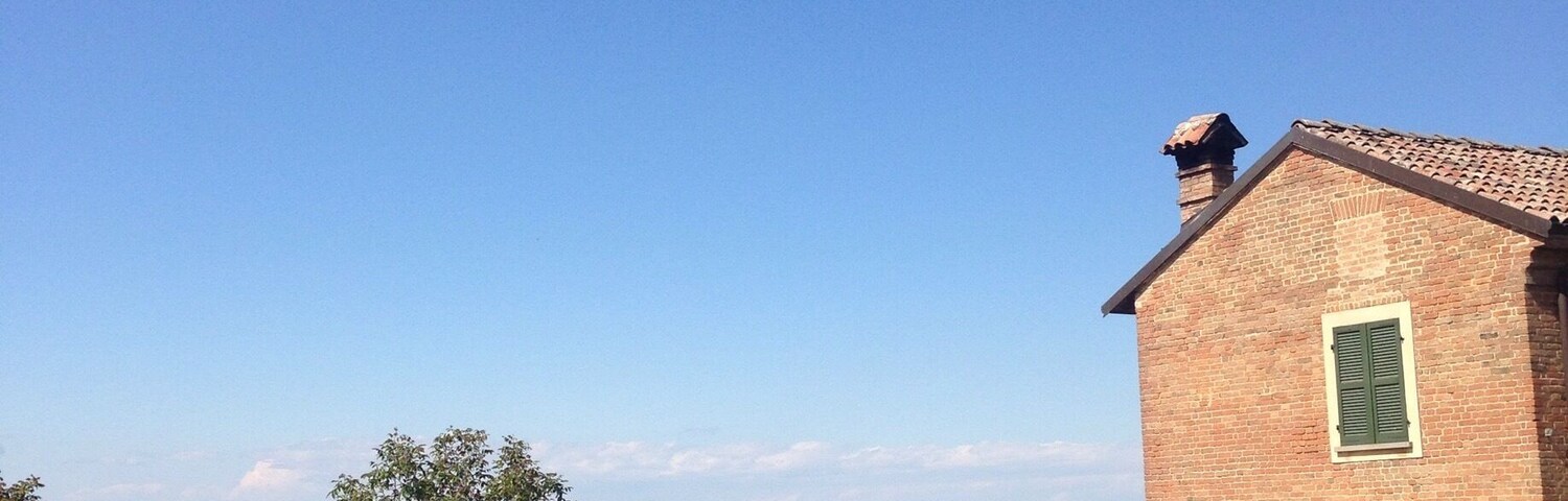 Ländliche Landschaft mit einem Backsteinhaus, einer Garage und einer Solaranlage.