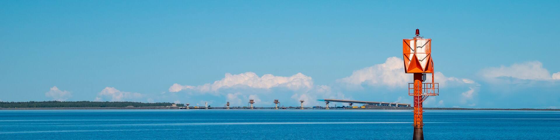 Finland, Oulu. The lighthouse in the strait between Oulunsalo and Hailuoto Island against a backdrop of beautiful clouds. In the background, a bridge under construction.