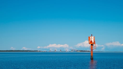 Finland, Oulu. The lighthouse in the strait between Oulunsalo and Hailuoto Island against a backdrop of beautiful clouds. In the background, a bridge under construction.