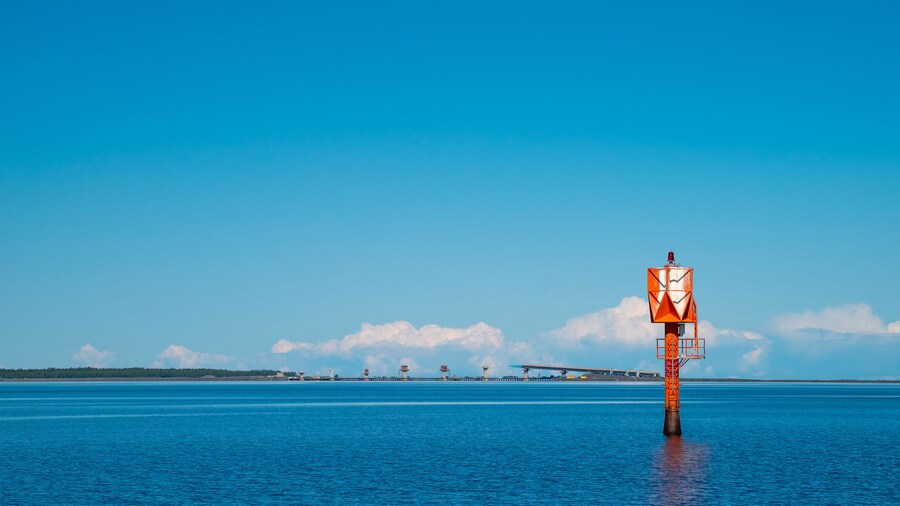 Finland, Oulu. The lighthouse in the strait between Oulunsalo and Hailuoto Island against a backdrop of beautiful clouds. In the background, a bridge under construction.