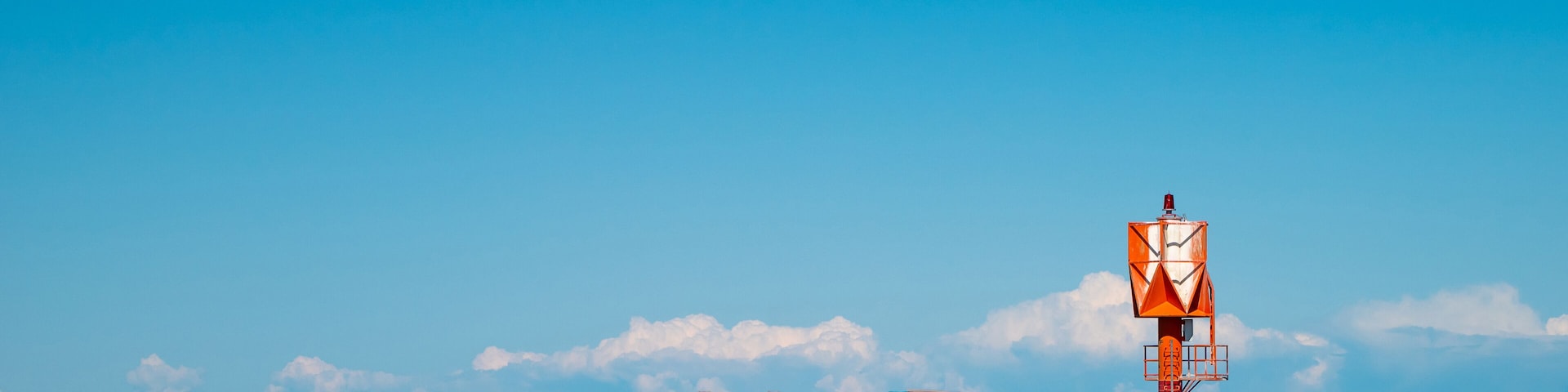 Finland, Oulu. The lighthouse in the strait between Oulunsalo and Hailuoto Island against a backdrop of beautiful clouds. In the background, a bridge under construction.