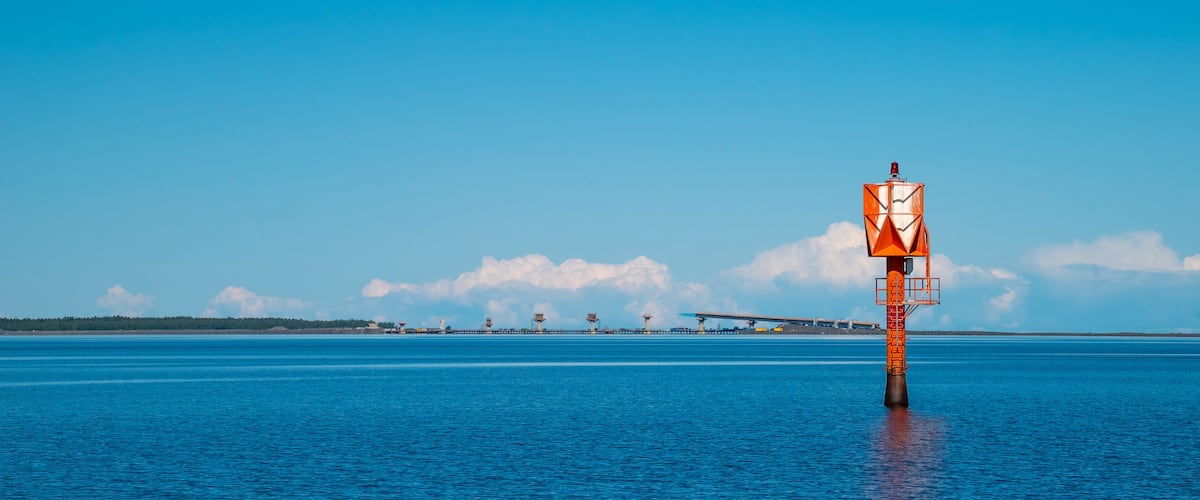 A lighthouse on a pier with a clear blue sky and calm water.