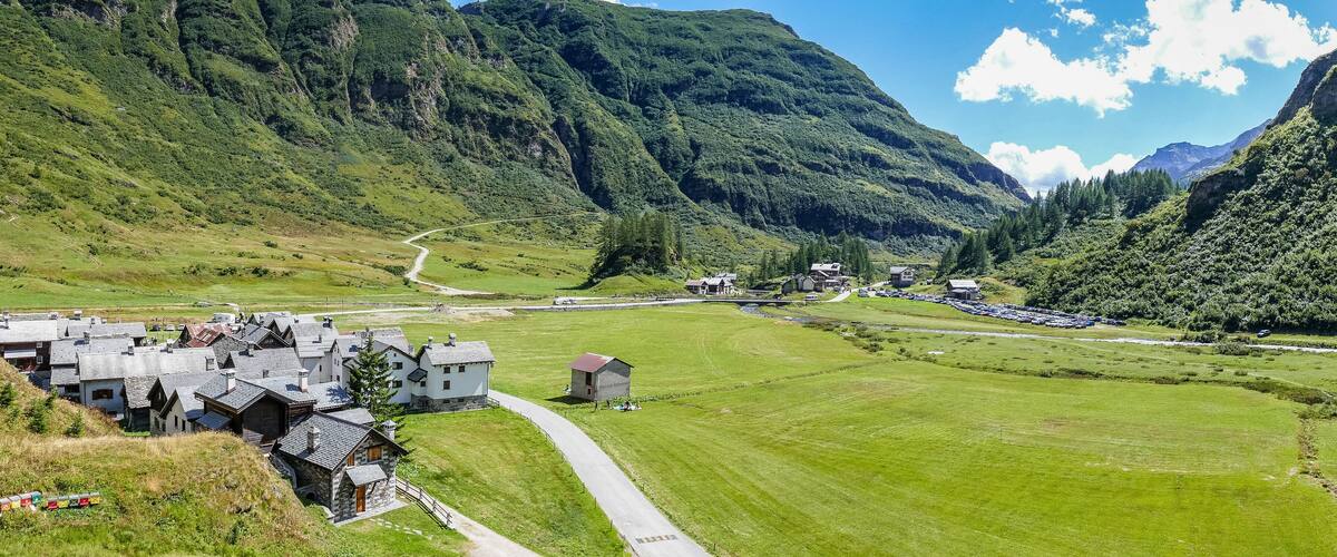 A mountainous village with houses, a winding road, and a river.