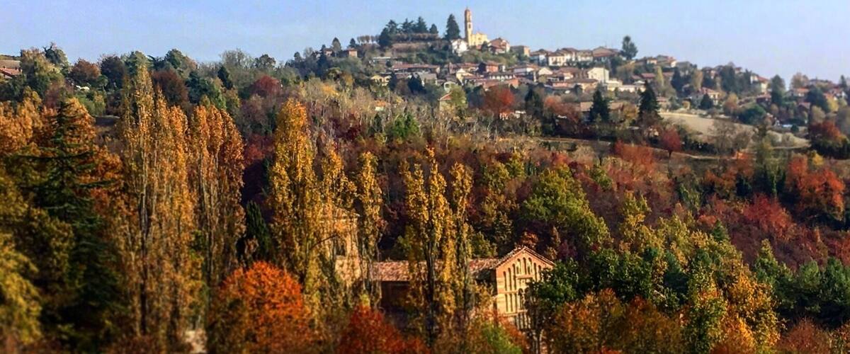 A hillside village with autumn foliage, a prominent church, and a tower in the background.