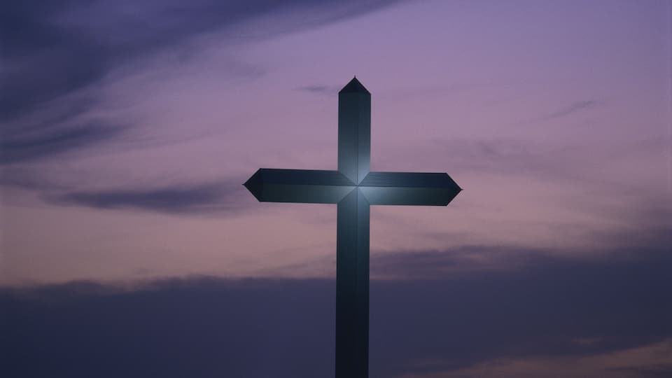 A cross against a twilight sky.