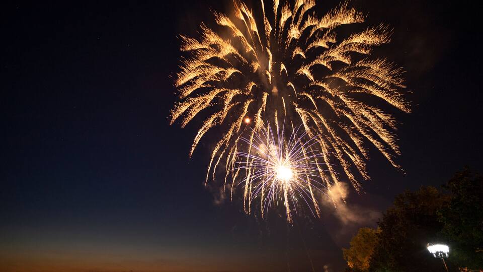 A night sky with a large, bright firework display.
