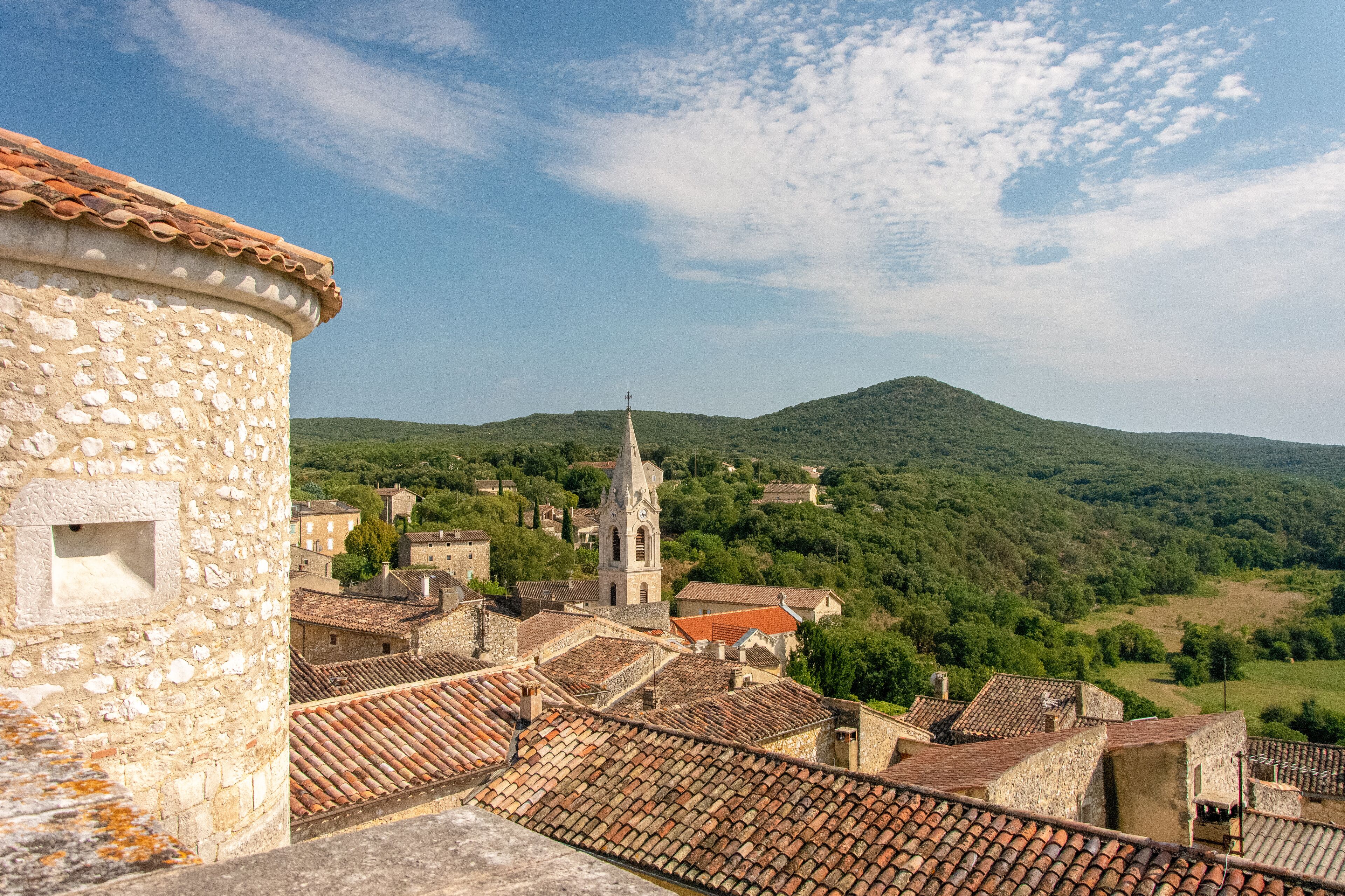 A stone tower, a church with a bell tower, and a village with terracotta roofs.