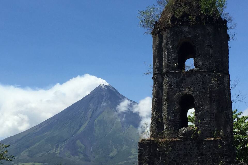 A mountain with a church bell tower in the foreground.