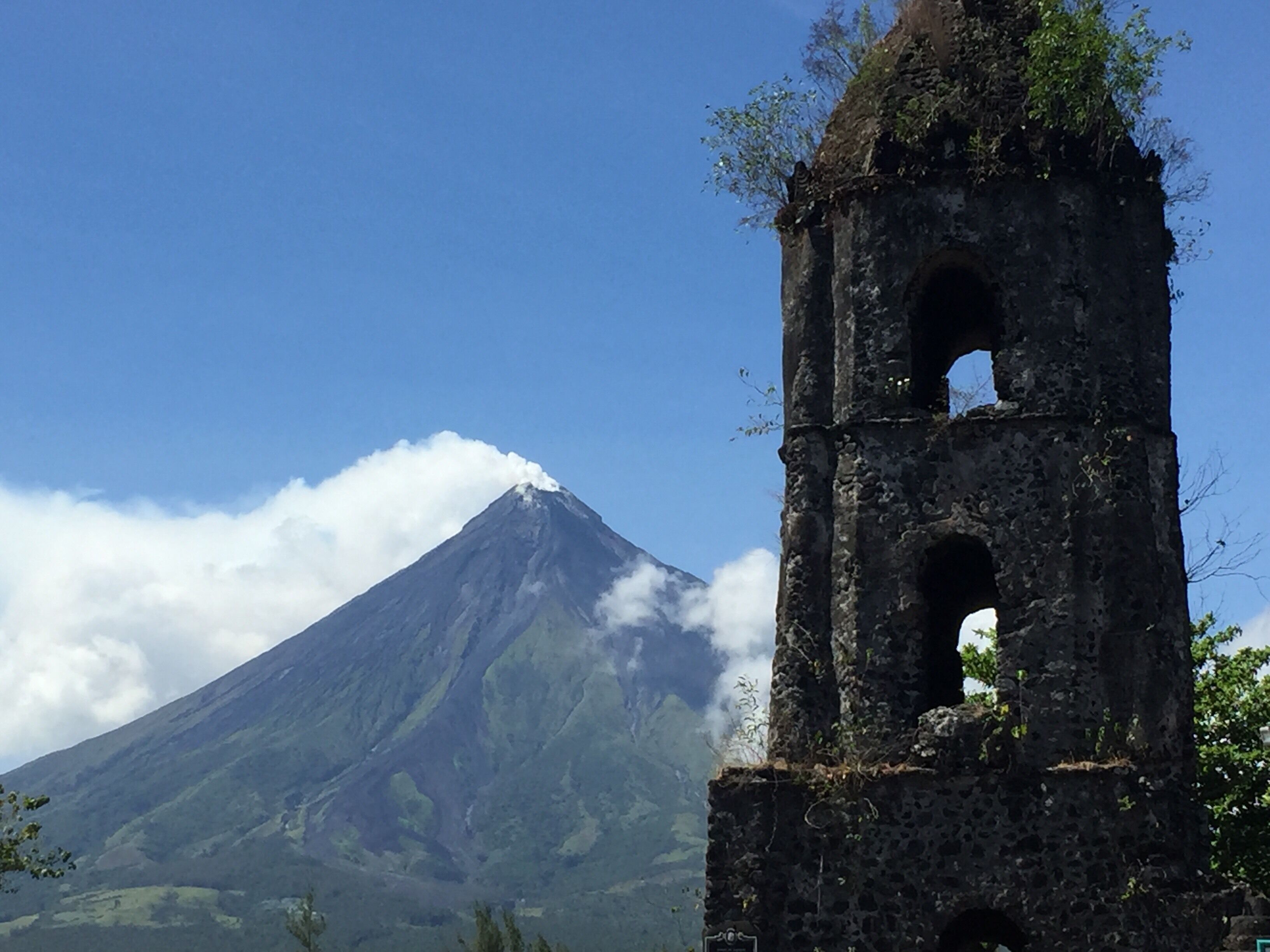 A mountain with a church bell tower in the foreground.