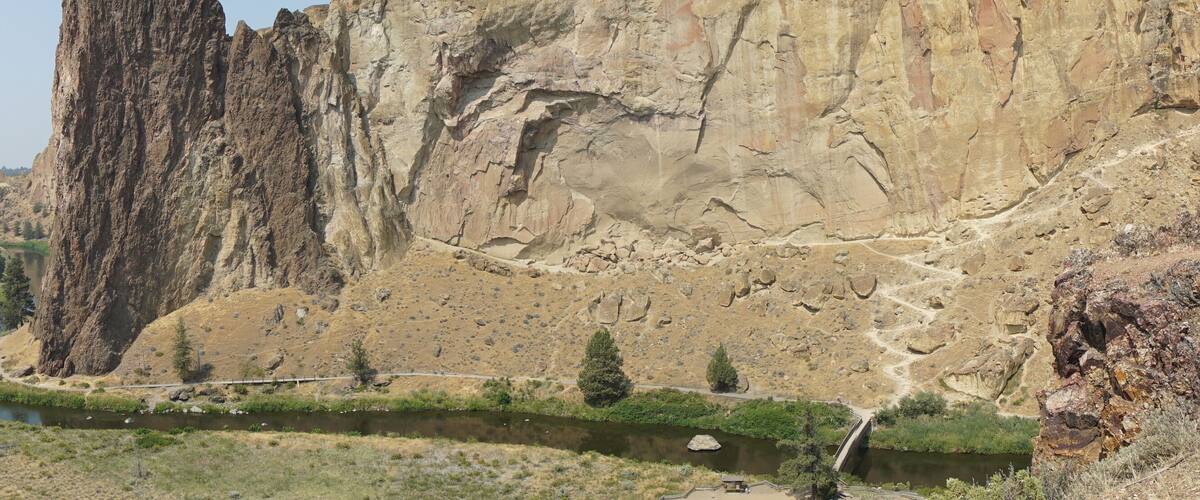 A river winding through a canyon with tall cliffs and sparse vegetation.