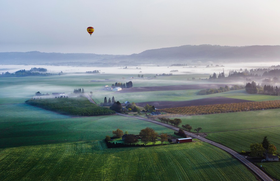 View of hot air balloon flying over rural landscape