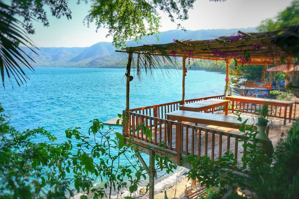 A wooden deck overlooking a calm lake with mountains in the background.