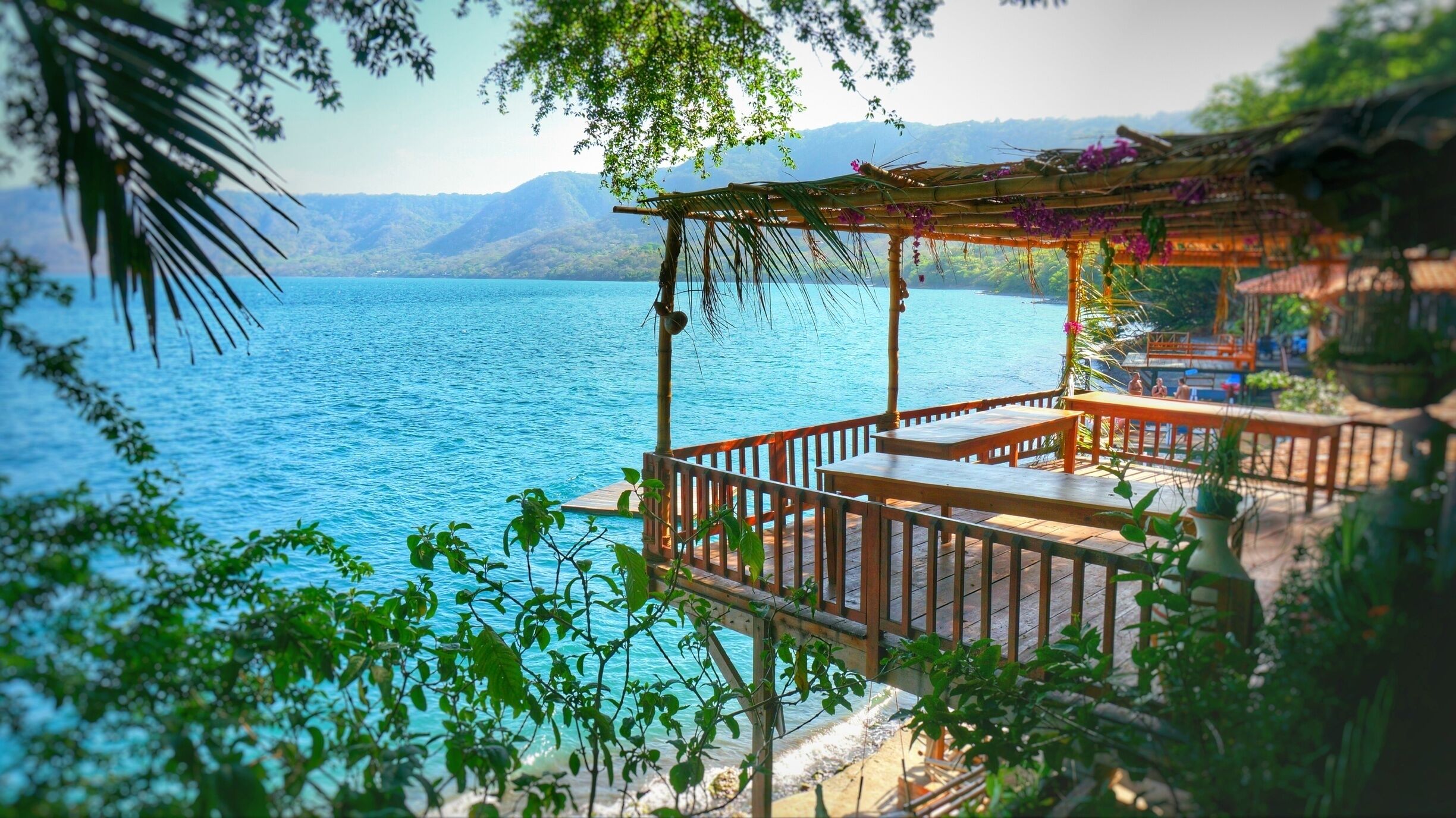 A wooden deck overlooking a calm lake with mountains in the background.