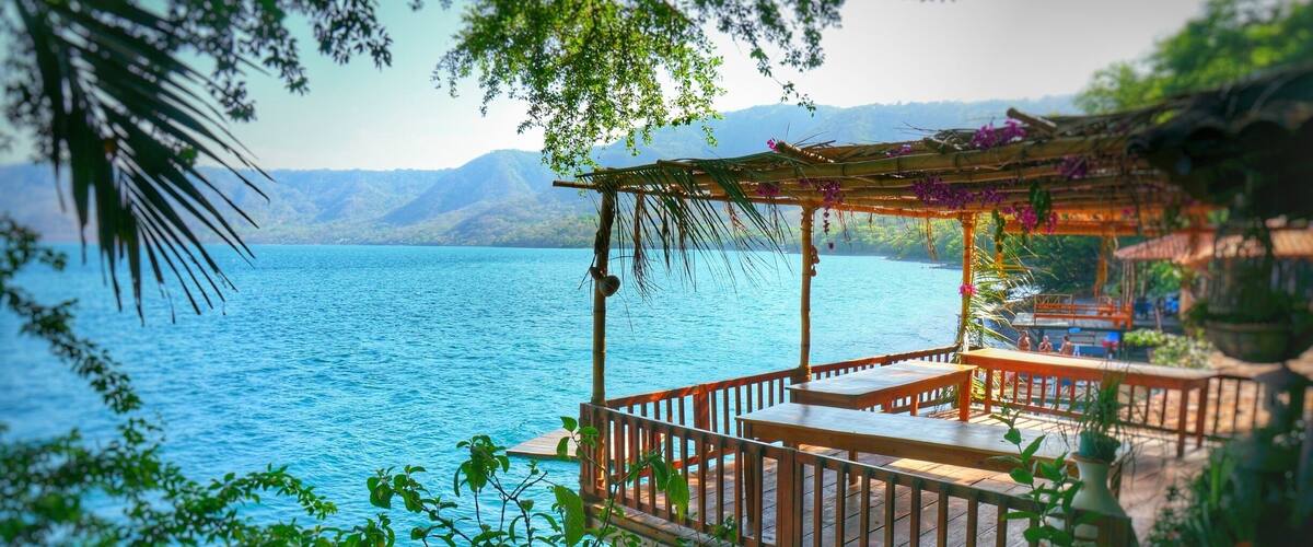 A wooden deck overlooking a calm lake with mountains in the background.