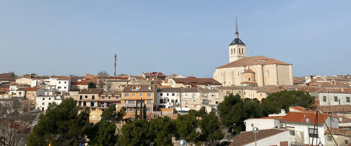 A town with historic buildings, a prominent church with a tall bell tower, and a clear blue sky.
