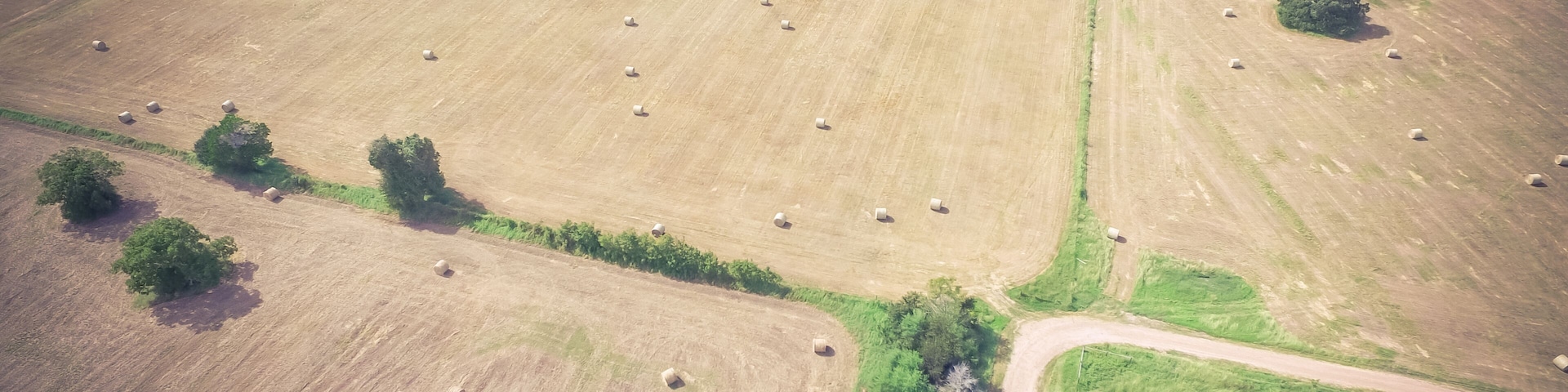 Vintage aerial prairie field at Texas Hill Country sunny day. Bale hay bales strewn across the farm after harvest. Rural landscape pasture Texas ranch farmland in summer time. Agriculture background