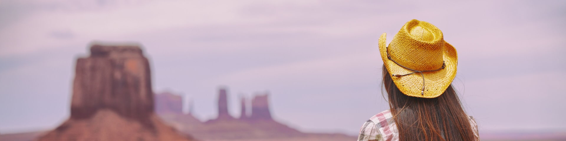 Cowgirl woman enjoying view of Monument Valley in cowboy hat. Beautiful young girl in outdoors, Arizona Utah, USA. Banner panorama.