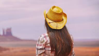 Cowgirl woman enjoying view of Monument Valley in cowboy hat. Beautiful young girl in outdoors, Arizona Utah, USA. Banner panorama.