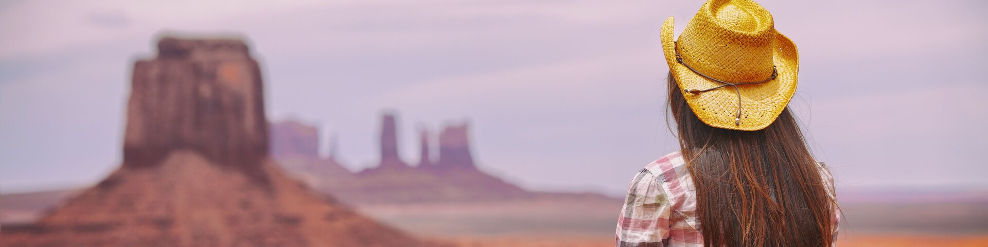 Cowgirl woman enjoying view of Monument Valley in cowboy hat. Beautiful young girl in outdoors, Arizona Utah, USA. Banner panorama.