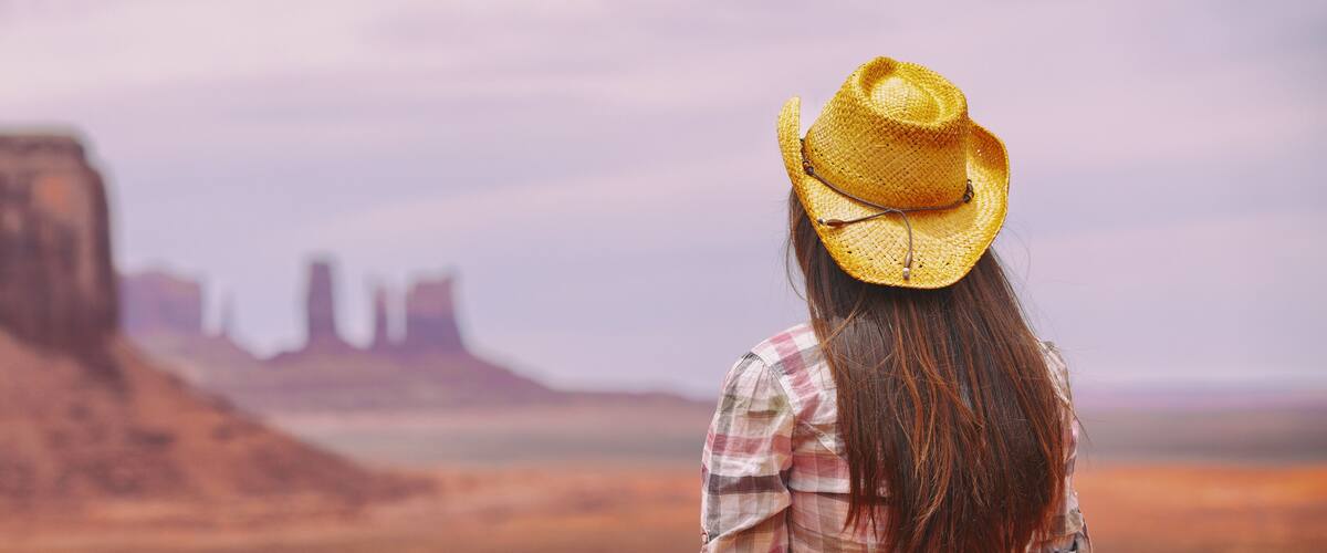 A desert landscape with a prominent rock formation and distant buildings.
