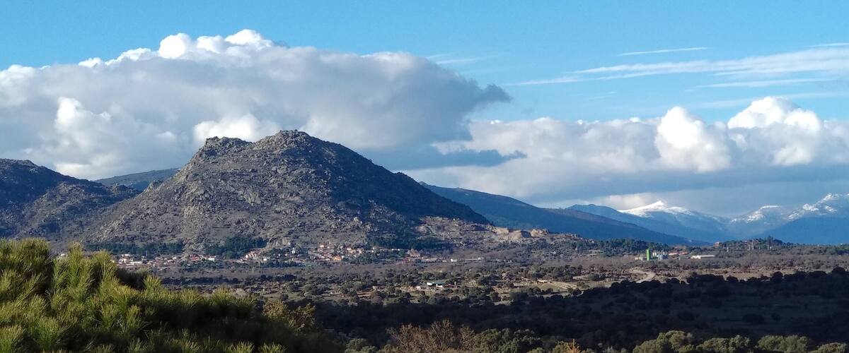 A mountain range with a village at its base, under a clear blue sky.