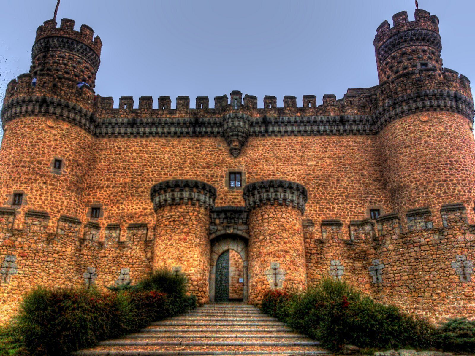 Un castillo de piedra grande con varias torres y una entrada principal.