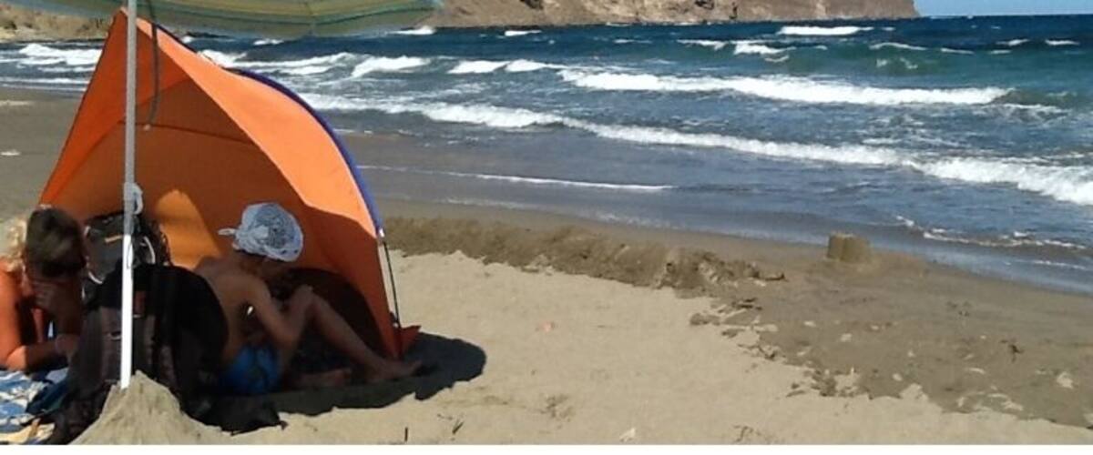 A beach with a tent and an umbrella.