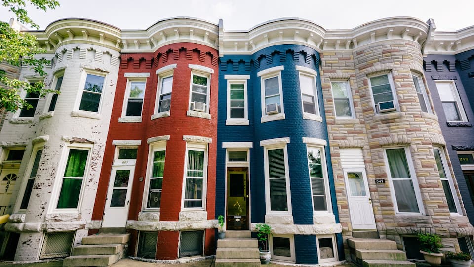 A row of colorful townhouses with distinct architectural styles and white trim.