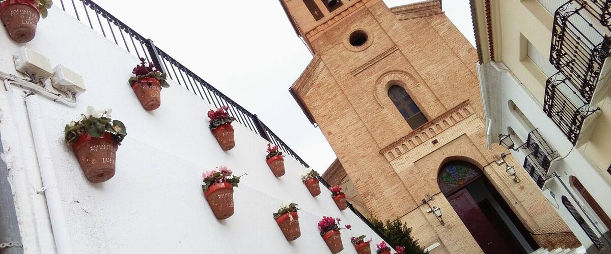A church with a bell tower and flower pots on the wall.