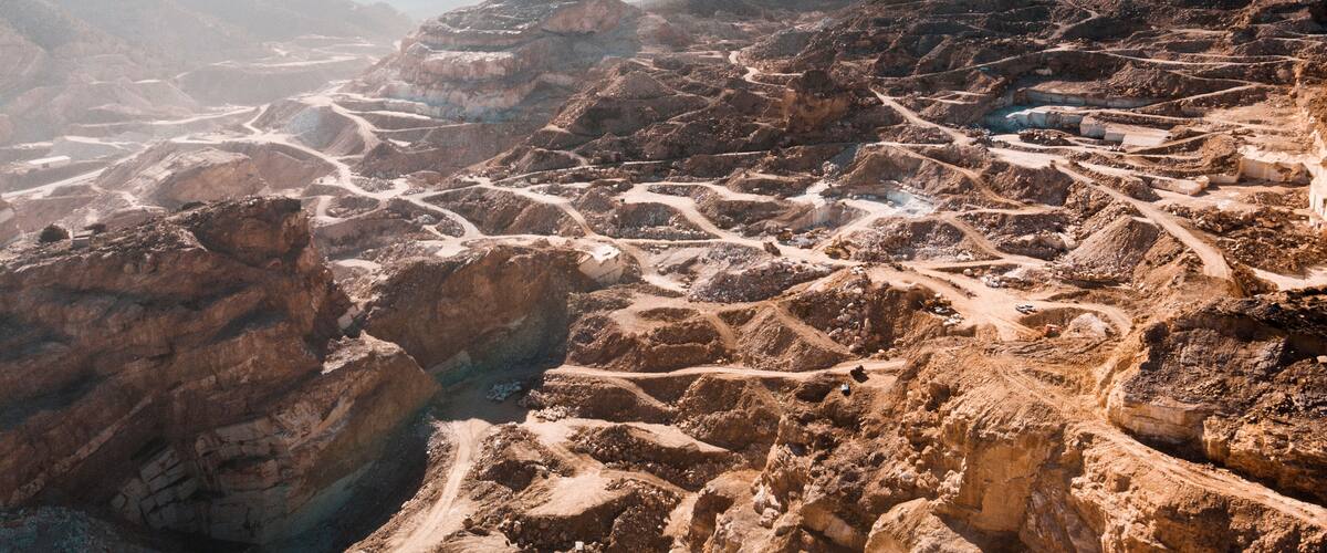 A vast, rugged terrain with layered rock formations and winding paths.