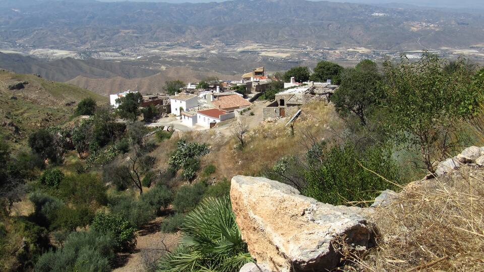A village on a hillside with a view of distant mountains.