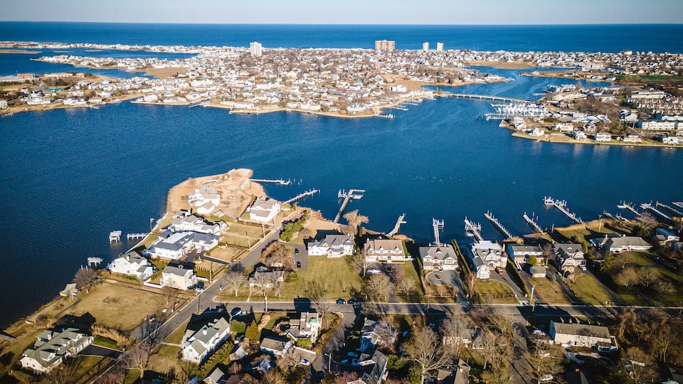An aerial view of a coastal town with a marina, residential areas, and a large body of water.