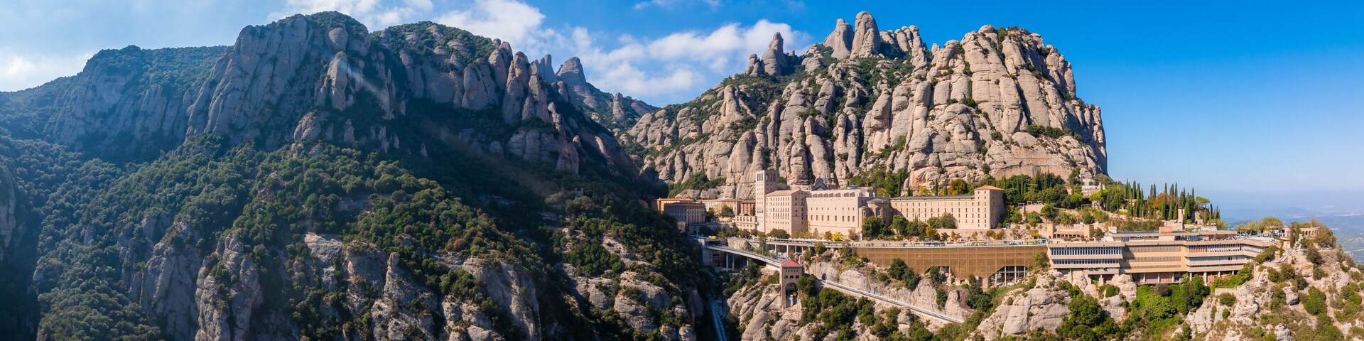 A mountainous landscape with a prominent rocky peak and a building complex on a hillside.