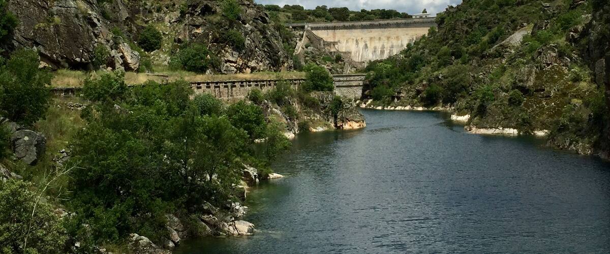 A river flowing through a rocky landscape with a dam in the background.