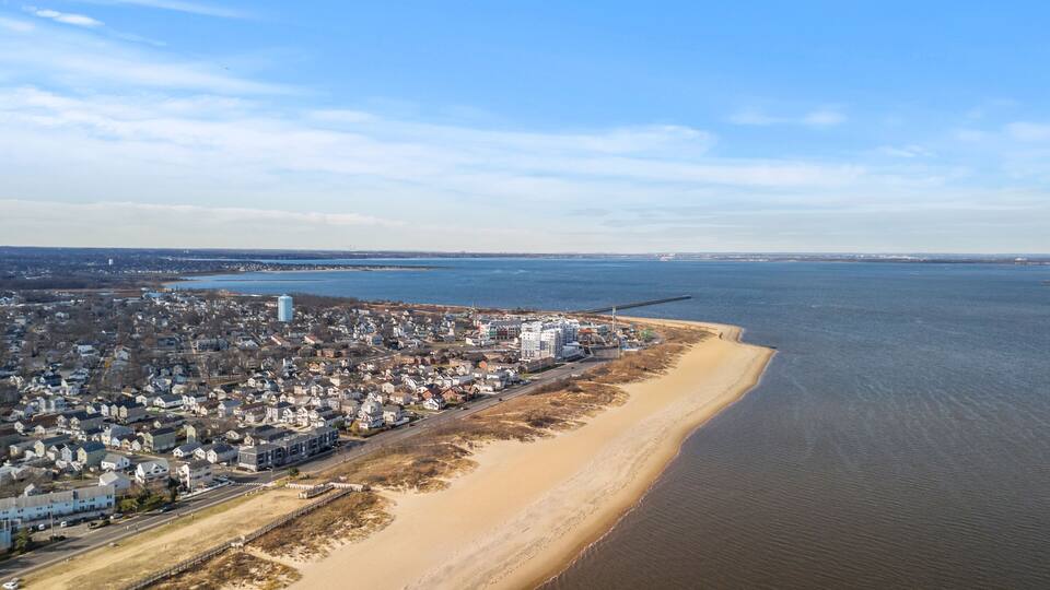 A coastal town with a beach, a large water body, and industrial structures.